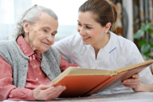 elderly woman with her caretaker reading a book